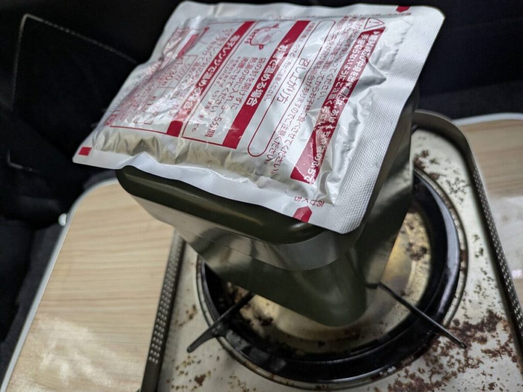 クッカーの上にレトルトカレーを乗せて温めている画像