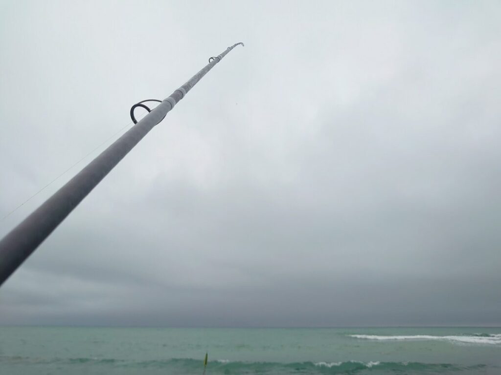 サーフで海に向かってロッドを持っている画像