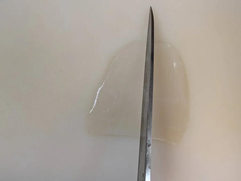 イカの胴を縦長に置き縦に切ろうとしている画像